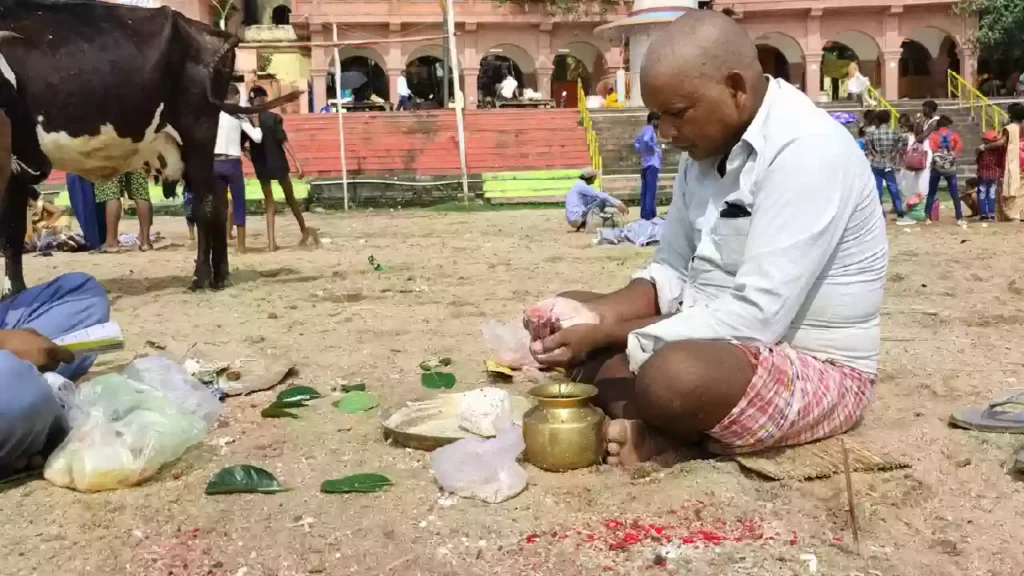 picture of a person seting near the ghat and performing the pind daan ritual for there ansester's on the time of Dwadashi Tithi 2025.