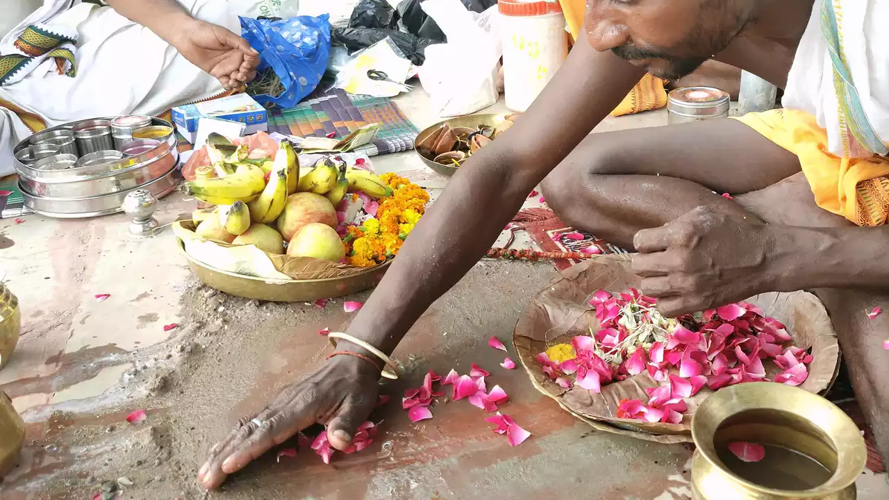 Man performs Tarpan (water offering) during Shraddha, with fruits and flowers nearby- Benefits of performing Shradh 