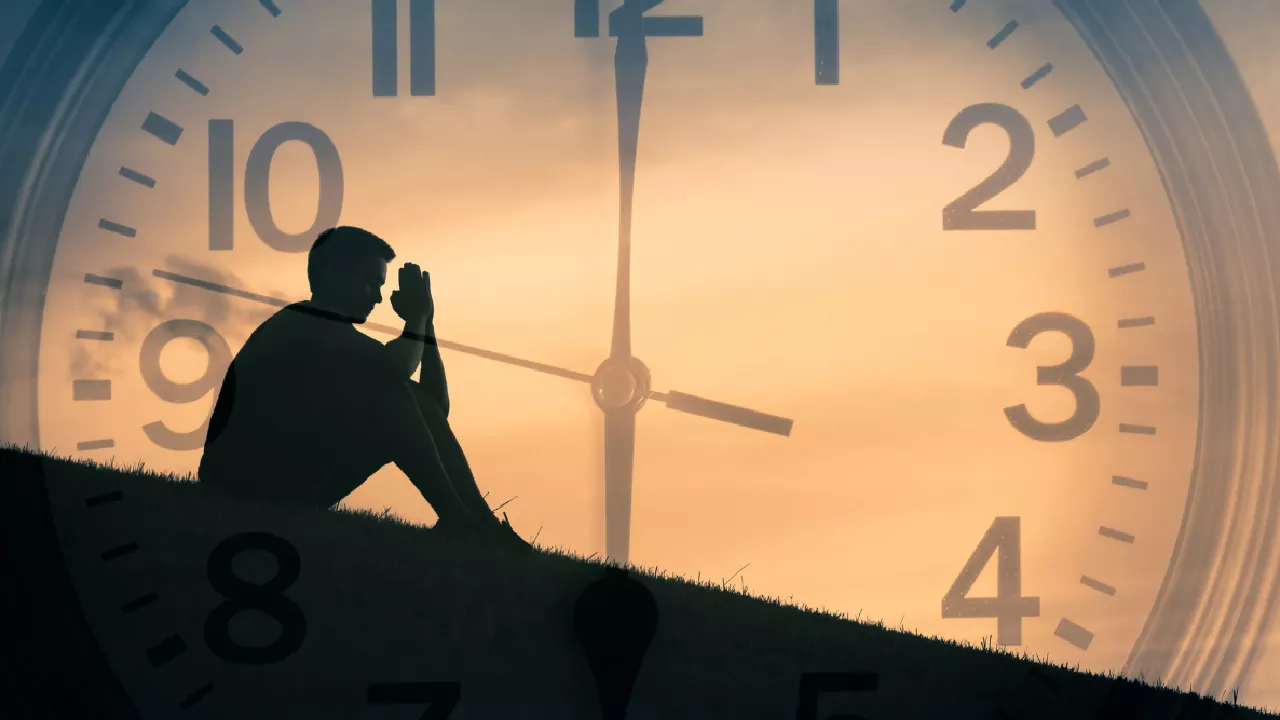 Image of a person sitting on a backdrop of a clock. Pitrupaksha and Self-Discovery
