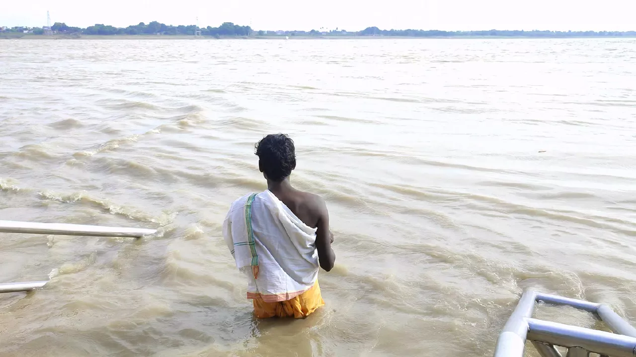 Photo of a person just about to immerse pindas in ganaga river. Pitrupaksha and Self-Discovery