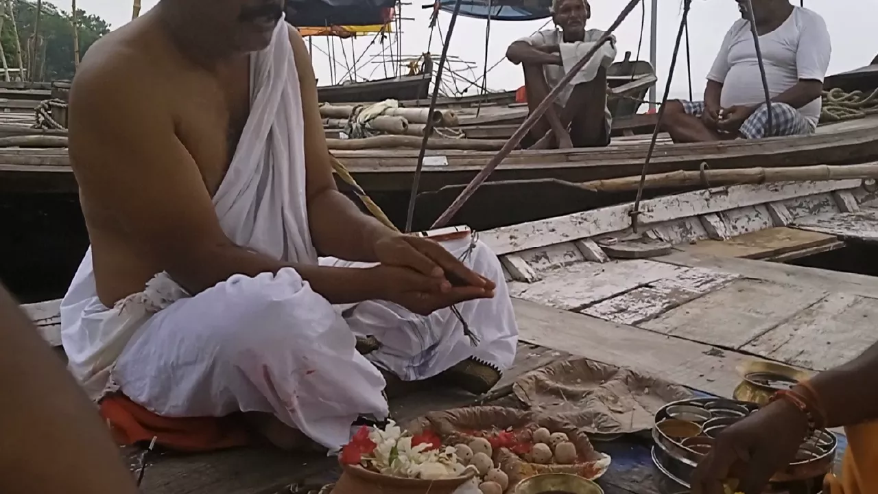 Image of a person siting on a boat and doing a ritual of their ansester's on time of Chaturdashi shradh untimely death