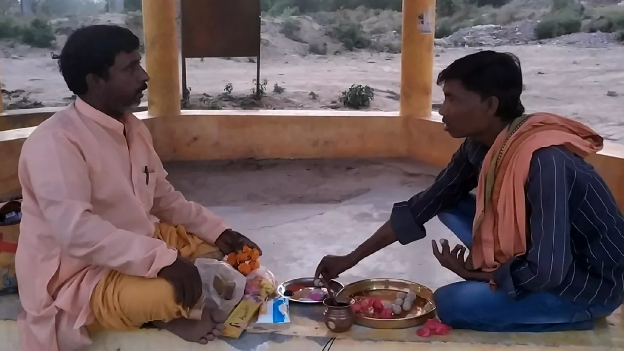 Two men sit facing each other, performing Pind daan ritual with Pindas and other offerings- Holy sites for Pind Daan