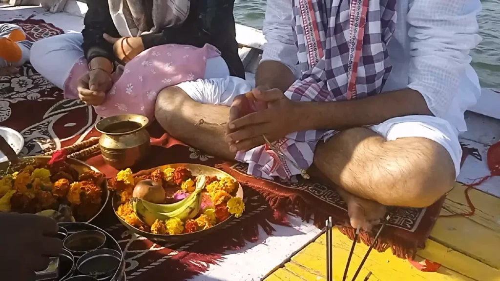 People on a boat are performing a Shradh ceremony with offerings of fruits, flowers, and incense- New Beginnings in Pitrupaksha