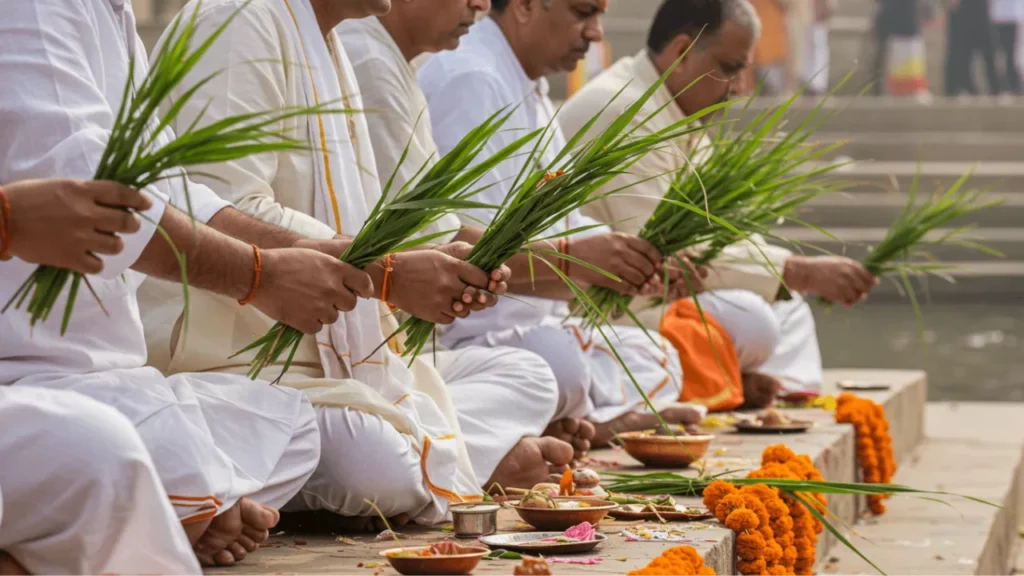 Image of Men in white attire sit by a ghat, holding kusha grass, preparing for Tarpan or Shraddh rituals- Kusha Grass Significance