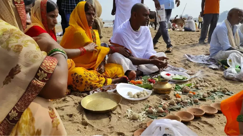 Image of People, including women in sarees, perform Pind Daan on a sandy riverbank with pindas and offeringe- Gaya Shradh Legends