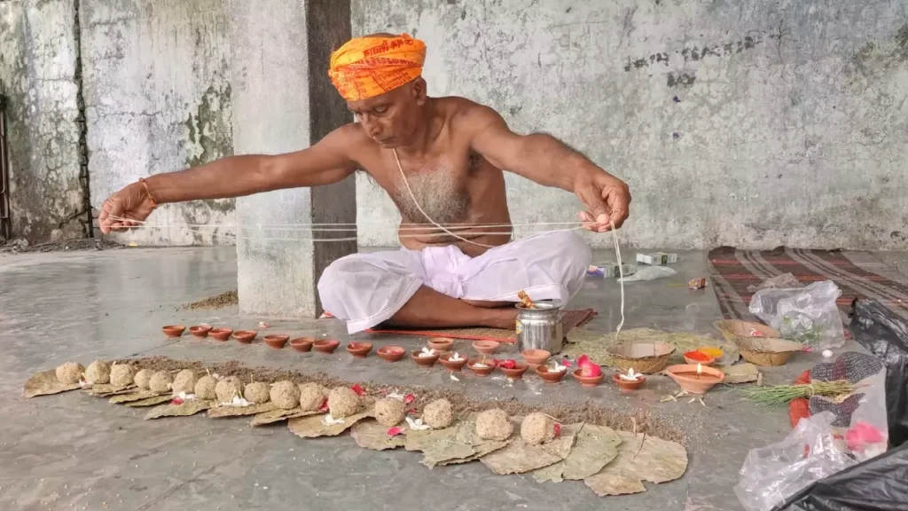 A Hindu priest performs the Pind Daan ritual, offering sacred water to the pindas and diyas for ancestors.